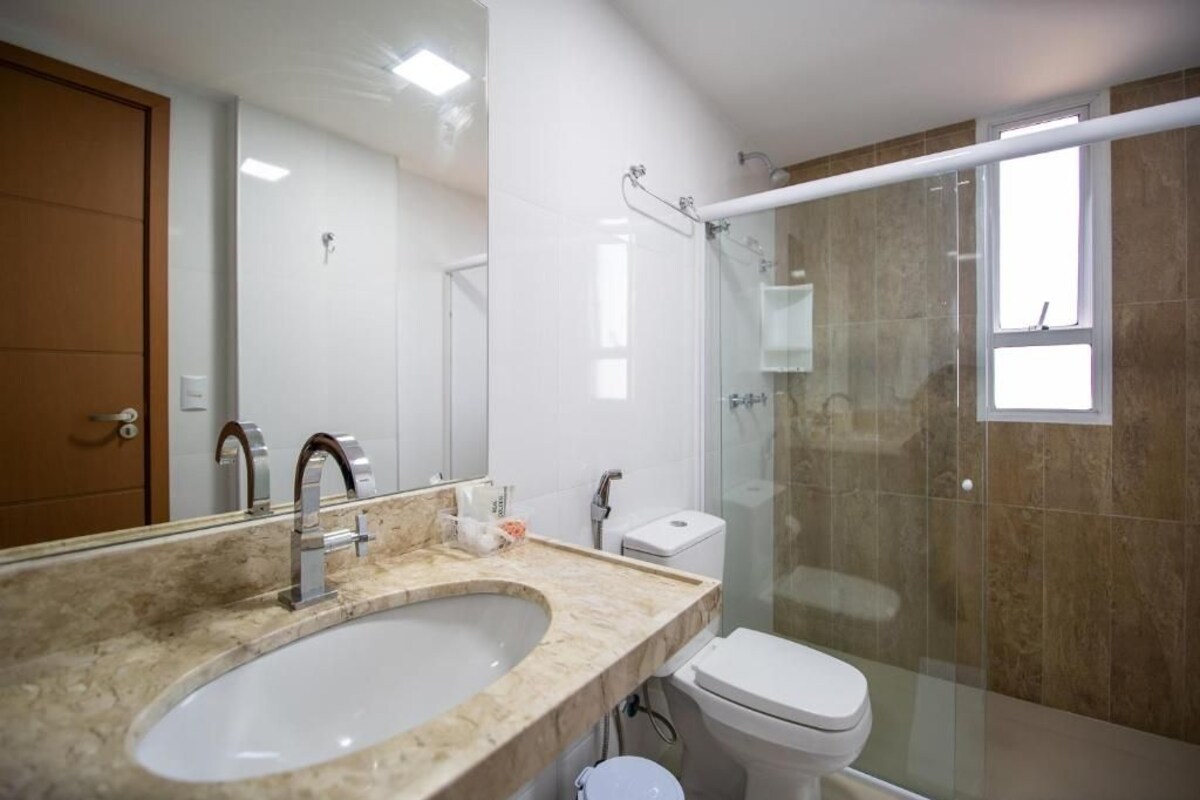 Une salle de bain avec un lavabo en marbre, des toilettes et une douche à parois de verre.
