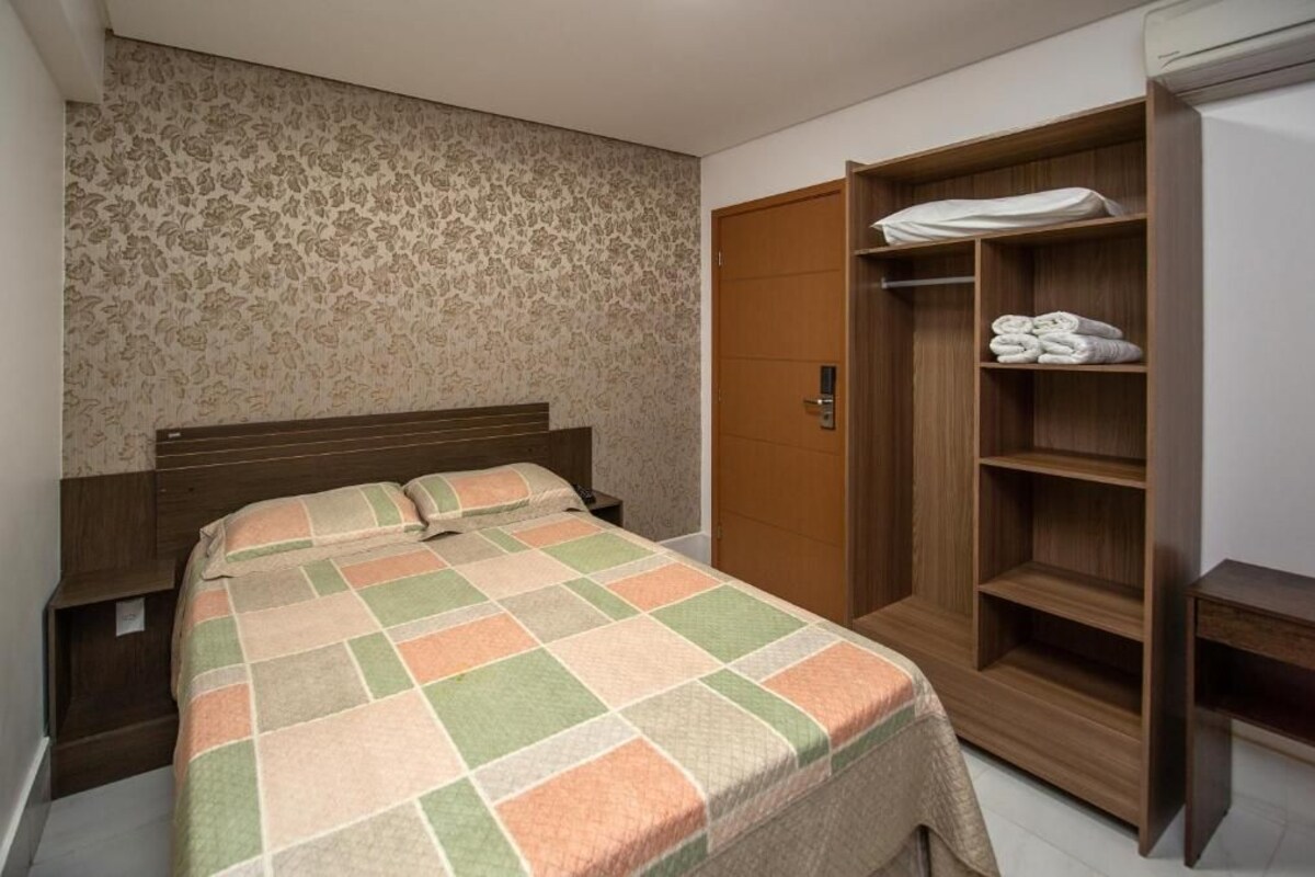 Une chambre à coucher avec un lit, une armoire en bois et un mur décoré d’un motif.