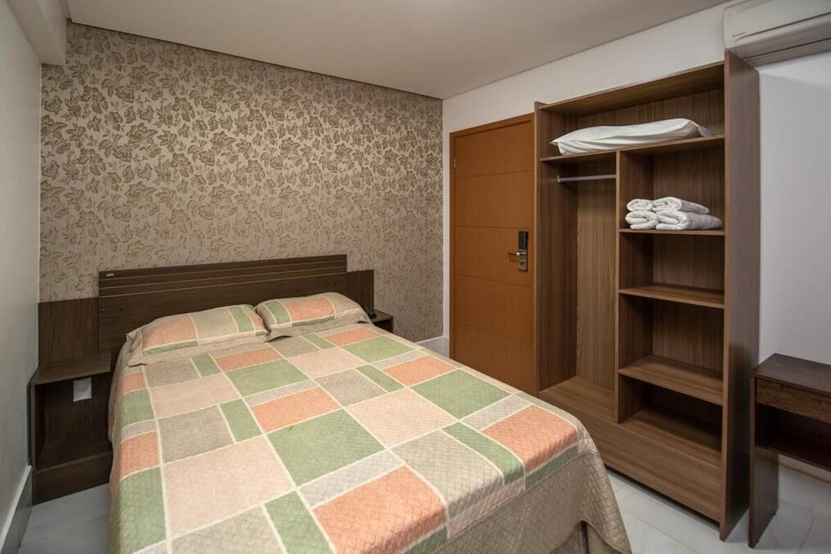 A bedroom with a bed, a wardrobe, and a nightstand.