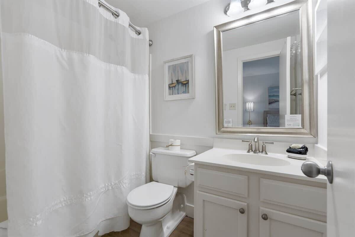 A bathroom with a white toilet, a sink, and a mirror.