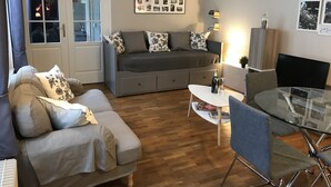 Een moderne woonkamer met een bank, een glazen eettafel en een televisie.
