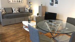 Een moderne woonkamer met een grijze bank, een glazen eettafel en grijze stoelen.