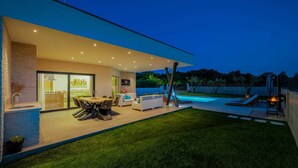 Ett modernt hus med en swimmingpool, utomhusmöbler och en väl upplyst uteplats.