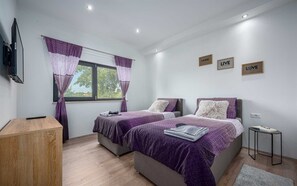 A modern bedroom with two beds, a TV, and a small table.