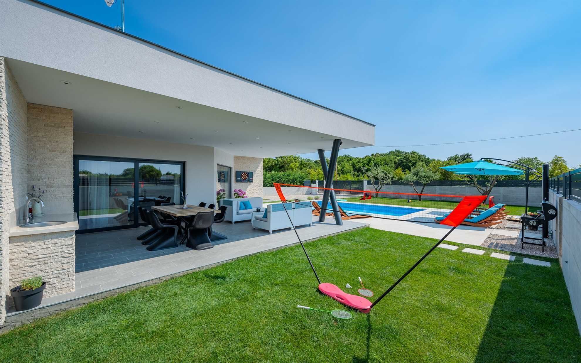 A modern outdoor living area with a pool, a swing set, and a dining area with outdoor furniture.