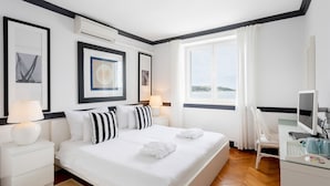 A hotel room with a large bed, two bedside tables with lamps, a TV, and framed pictures on the wall. - Villa Dubrovnik Secret Escape with Pool (Dubrovnik)