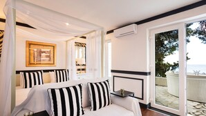 Ein Schlafzimmer mit Bett, Nachttischen, einem Spiegel und Blick ins Freie.