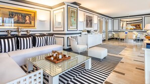 Ein modernes Wohnzimmer mit einer Couch, einem Couchtisch und einem Essbereich mit Stühlen sowie einer Küchenzeile.