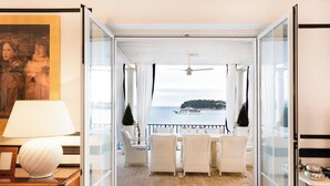 Ein Zimmer mit Meerblick, Korbsessel, ein Tisch und ein Deckenventilator.