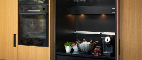 Een keuken met een Bosch magnetron, een koffieapparaat en een wijnkoeler met glazen.