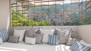 Un rincón acogedor con asientos y vistas a un paisaje montañoso a través de una ventana con persianas de madera.