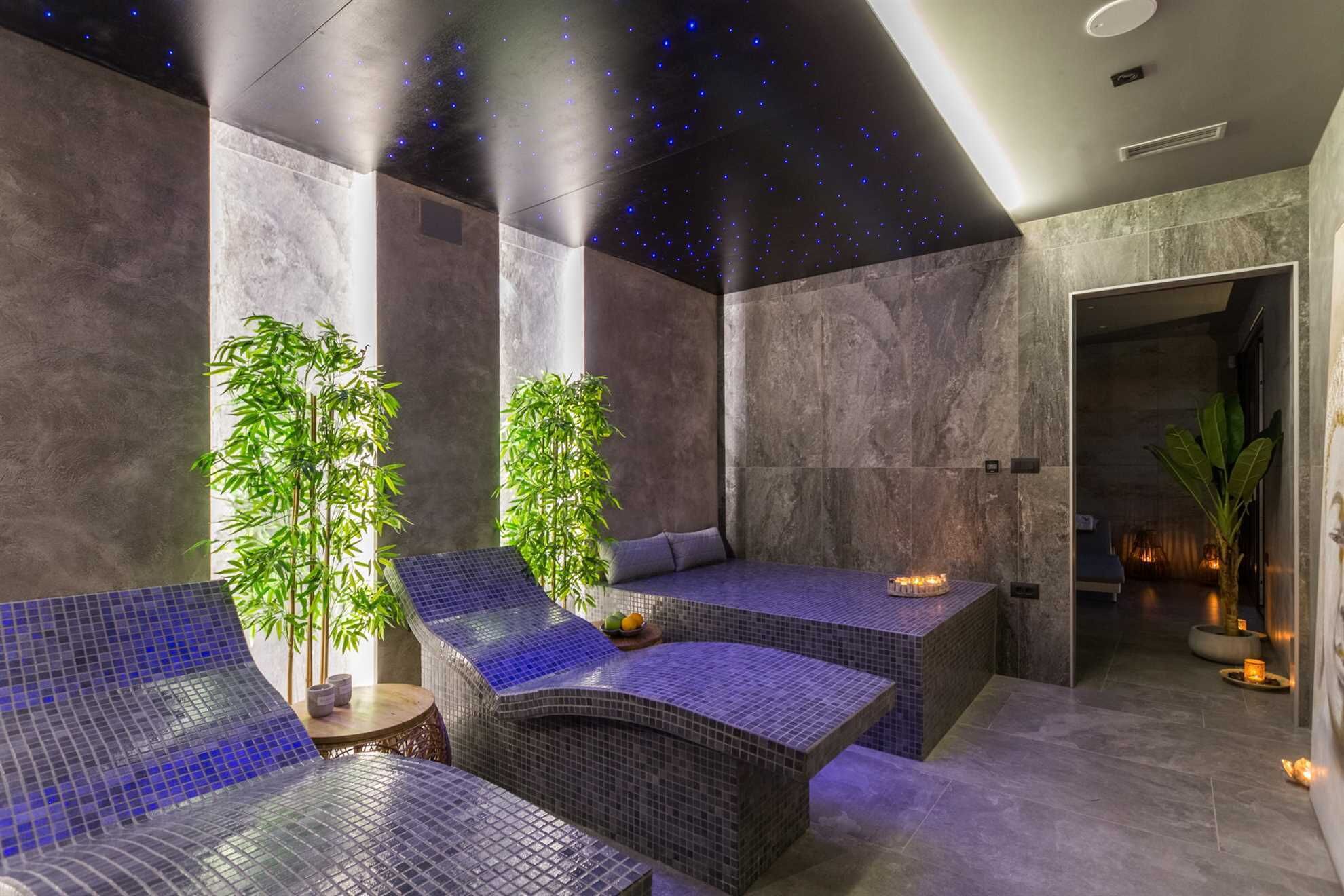 A modern spa area with seating, plants, and a starry ceiling.