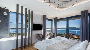 A modern bedroom with a large bed, a TV, and a view of the sea. - Villa La Vie with Pool (Medulin)
