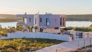 A modern two-story building with a flat roof, large windows, and a view of a lake. - Villa La Vie with Pool (Medulin)
