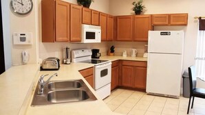 Una cucina con mobili in legno, un frigorifero bianco, un forno a microonde, un piano cottura e un lavandino.