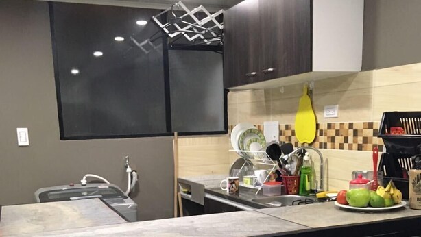 A modern kitchen with black and white cabinetry, a black countertop, and two white bar stools. - independent apartment near airport photos prints visa american embassy (Bogotá)