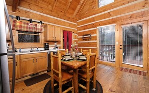 Uma cozinha acolhedora em estilo cabana, com armários de madeira, uma mesa de jantar e uma janela com persianas.