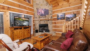 Un interior de cabaña acogedor con chimenea de piedra, muebles de madera y obras de arte en las paredes.