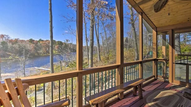 A wooden deck with benches overlooking a lake surrounded by trees. - Secluded Waterfront Cabin on hiking trails! Lake on one side river on the other. (Luck)