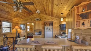 A wooden cabin interior with a kitchen, dining area, and a bar. - Secluded Waterfront Cabin on hiking trails! Lake on one side river on the other. (Luck)
