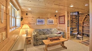 A cozy cabin interior with a wooden ceiling, a sofa, a coffee table, and a ladder. - Secluded Waterfront Cabin on hiking trails! Lake on one side river on the other. (Luck)