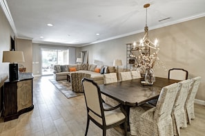 A spacious living room with a large dining table, comfortable seating, and a chandelier. - The Great Escape - Indio - Across from Coachella (Indio)
