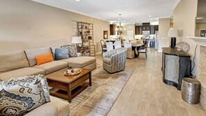 A spacious living room with a sofa, coffee table, and patterned rug. A dining area with chairs and a table is visible in the background. - The Great Escape - Indio - Across from Coachella (Indio)