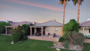 A residential property with a covered patio, outdoor seating, and a well-maintained lawn.