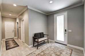 A hallway with a bench, a door with a window, and a light fixture on the ceiling.