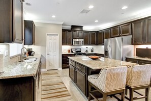 Una cocina moderna con armarios de madera oscura, electrodomésticos de acero inoxidable y encimera de granito.