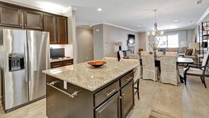 A modern kitchen with a large island, stainless steel appliances, and a dining area with a chandelier. - The Great Escape - Indio - Across from Coachella (Indio)