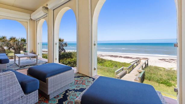 A covered outdoor seating area with wicker furniture and a view of the beach. - Captivating & Spacious 2 primary suites/2.5 bath Oceanfront Condo  (Indialantic)