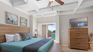 A bedroom with a bed, wooden headboard, a ceiling fan, a TV, and a view to the outside. - Captivating & Spacious 2 primary suites/2.5 bath Oceanfront Condo  (Indialantic)