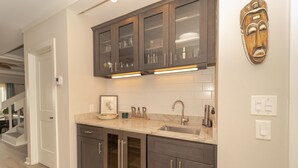 A kitchen with dark cabinets, a marble countertop, and a wooden mask on the wall. - Captivating & Spacious 2 primary suites/2.5 bath Oceanfront Condo  (Indialantic)