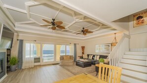A spacious living room with a wooden dining table, a sofa set, and a staircase. - Captivating & Spacious 2 primary suites/2.5 bath Oceanfront Condo  (Indialantic)