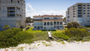 A beachfront hotel with multiple floors, a central courtyard, and a sandy beach area. - Captivating & Spacious 2 primary suites/2.5 bath Oceanfront Condo  (Indialantic)