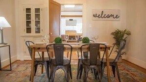 A dining area with a wooden table and chairs, a 'welcome' sign, and a view into the kitchen. - Fenced-In Yard & Nice Patio! Capital State Heights (Montgomery)