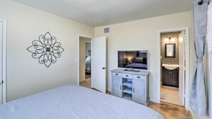 A bedroom with a bed, a TV, a vanity, and a bathroom visible through an open door. - Southwest Sanctuary! Tucson Home w/ Patio & Yard (Tucson)