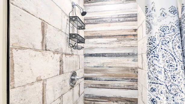 A bathroom with a tiled wall, a shower with a handheld showerhead, and a patterned curtain. - Southwest Sanctuary! Tucson Home w/ Patio & Yard (Tucson)