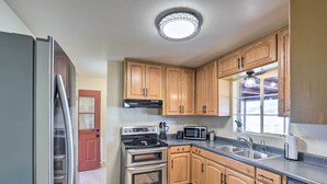 A kitchen with wooden cabinets, stainless steel appliances, a microwave, and a built-in oven. - Southwest Sanctuary! Tucson Home w/ Patio & Yard (Tucson)