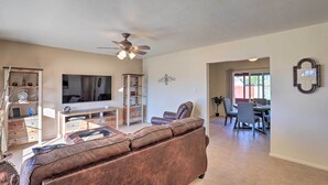 A spacious living room with a brown leather sofa, a flat-screen TV, a ceiling fan, and a dining area with chairs and a table. - Southwest Sanctuary! Tucson Home w/ Patio & Yard (Tucson)