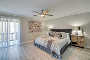 A bedroom with a bed, a ceiling fan, a nightstand, a lamp, and a window with blinds.