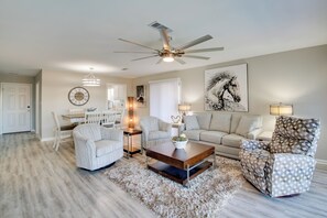 A living room with a ceiling fan, a coffee table, a sofa, and patterned armchairs.