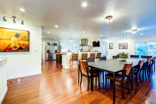A spacious kitchen with modern appliances, a dining area with wooden chairs, and a large window providing a view of the outdoors.