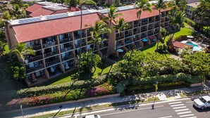 A multi-story hotel with balconies, a swimming pool, and lush landscaping.