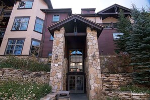 Stunning stone entrance with glass door and pillars, set amidst a beautifully landscaped area.