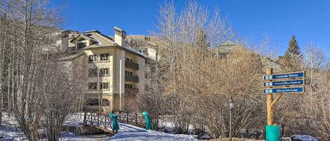 A snow-covered path leading to a building with a signpost indicating directions to Creekside Skiyway, Townend Place/Creekside, and Elkhorn Lift/Lodge.