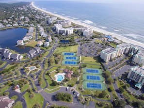 An aerial view of a coastal resort with multiple buildings, a beach, and a lake.