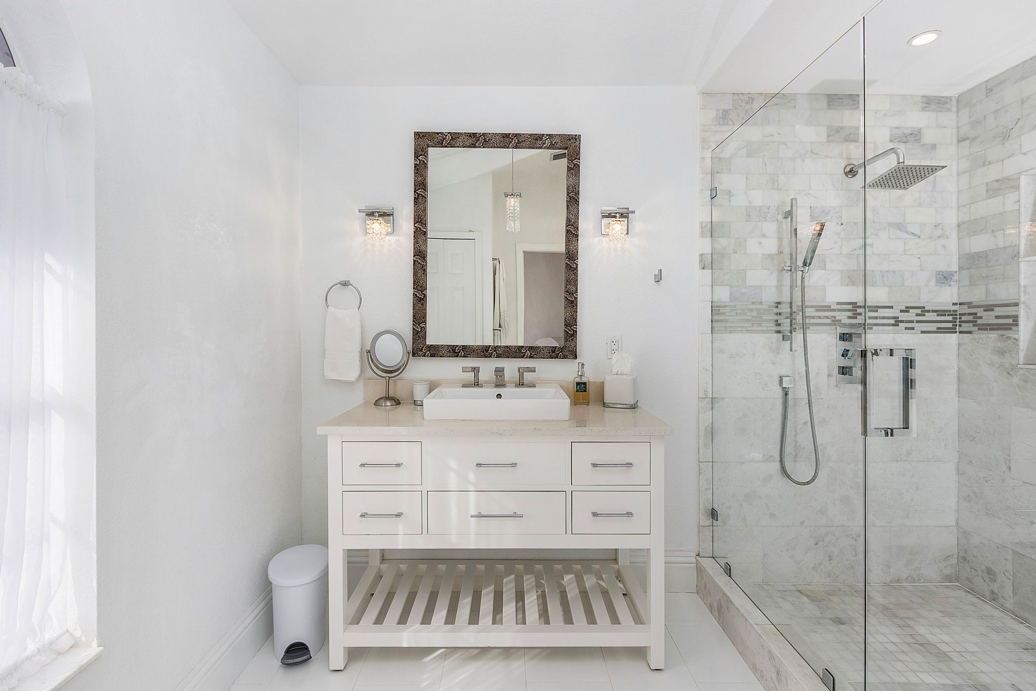 Un baño moderno con un espejo grande, tocador blanco y cabina de ducha acristalada.
