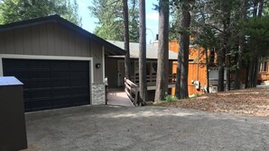 A two-story building with a garage, a covered porch, and a wooden deck.